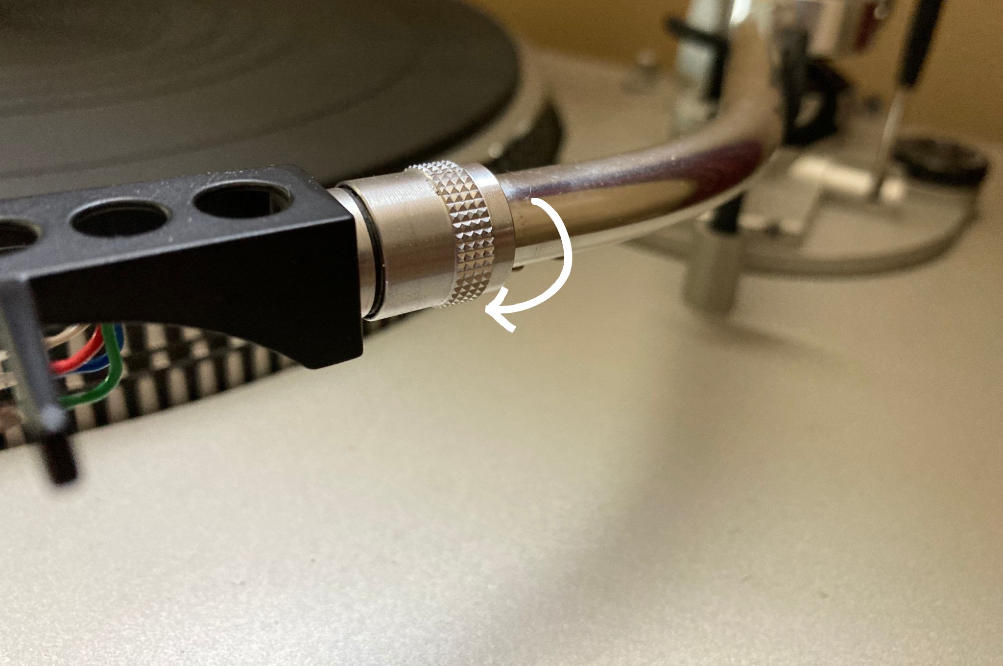 Turntable's tonearm ring being loosened to remove the headshell